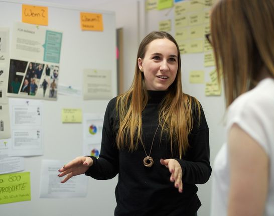 Junge IT-Consultant steht vor Board mit Post-its und erklärt