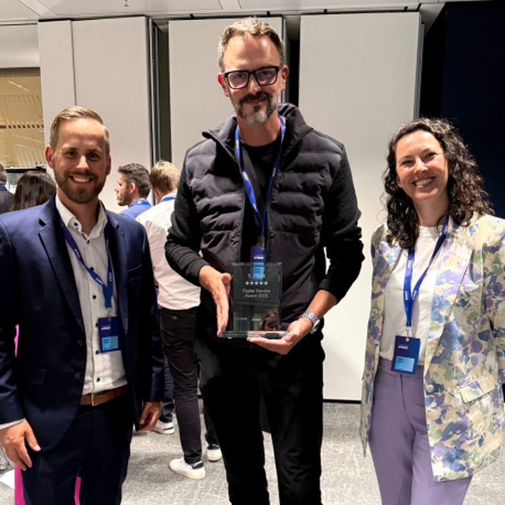 Drei dmTECH Mitarbeitende posieren stolz mit dem Digital Service Award 2025