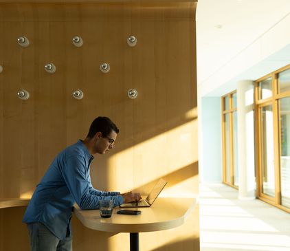 Junger Studierender arbeitet in Kaffeebar an Laptop